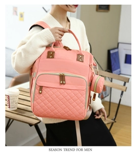Detail of pink quilted diaper backpack with gold zippers and detachable small round pouch