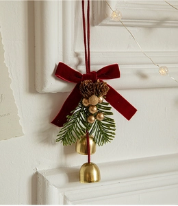 Detail of Christmas ornament with red velvet bow, pine cones and gold bells on a tree