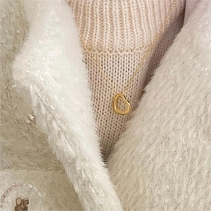 Close-up of a delicate gold heart pendant necklace on a minimalist thin chain