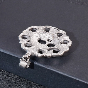 Close-up of vintage round silver hollow flower pendant with ornate bow bail connector