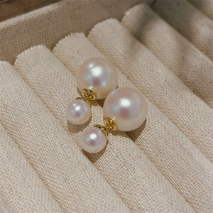 Detailed close-up of double pearl earrings with gold plating on a beige velvet jewelry box