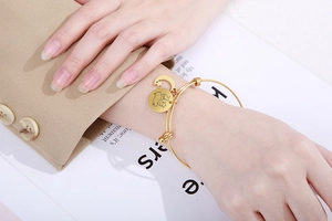 Detail of adjustable gold stainless steel bracelet with moon and star pendants on wrist