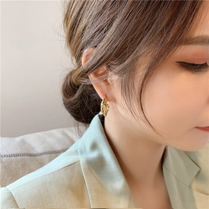 Close-up of elegant gold twisted double-layered hoop earrings worn by a female model