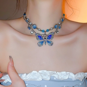 Détail du collier pendentif papillon bleu avec perles sur le cou du mannequin