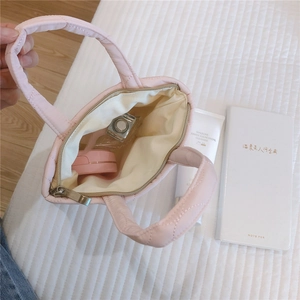 Dettaglio della mini borsa trapuntata rosa che mostra fodera interna e piccoli cosmetici