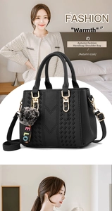 Detail of black pebbled leather handbag with grey faux fur pompom and 'LOVE' strap ribbon