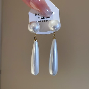 Detail of drop-shaped pearl earrings showing the smooth texture and gold metal connector