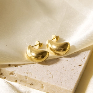 Polished 18k gold plated hollow teardrop earrings on a stone base and cream silk fabric