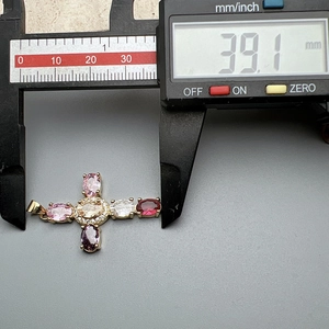 Detail showing the 39.1 mm width of a colorful zircon cross pendant using a digital caliper