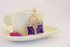 Detailed macro shot of golden handbag keychain featuring purple gems and sparkling rhinestones