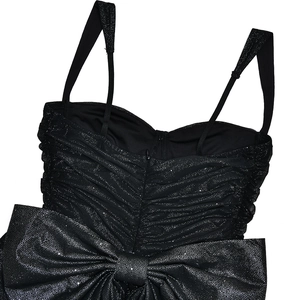 Close-up of black sparkly dress featuring pleated bodice, spaghetti straps and oversized bow