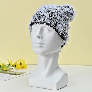Detail of black and white fuzzy knit beanie with long plush texture on a mannequin head
