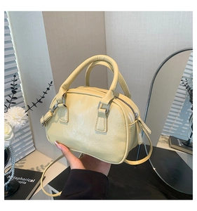 Detail of yellow Boston bag with retro faux leather texture and metallic hardware