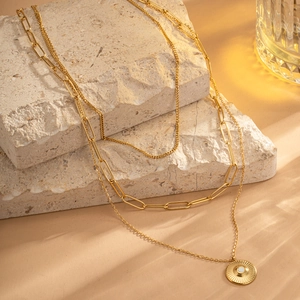 Three-layer gold titanium steel necklace set with sunburst pendant on stone base
