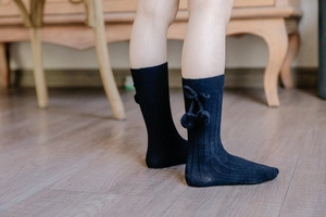 Detail of black cotton ribbed socks with 3D pom-poms and cute bows for kids