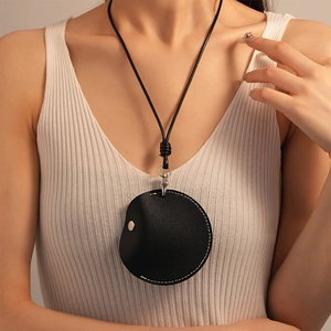 Detail of round black leather mini bag necklace with contrast stitching and silver snap button