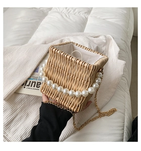 Detail of hand-woven straw bag with faux pearl handle and gold chain strap