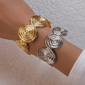 Detail of spiral textured metal bangles in gold and silver finish worn by a model