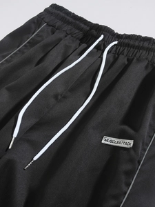 Detail view of men's black joggers featuring elastic waistband and white drawstrings