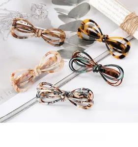 Close-up of tortoise shell and marble pattern acetate bow hair clips in various colors