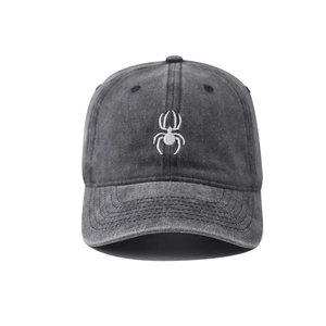 Detailed close-up of white spider embroidery on washed grey cotton canvas baseball cap