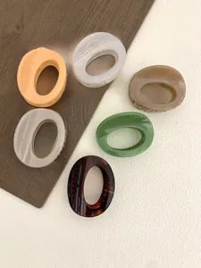 Close-up of large oval matte hair claws in orange, white, khaki, grey and tortoiseshell