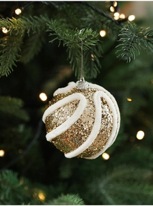 Nahaufnahme einer goldenen Weihnachtskugel mit weißen Plüschstreifen am Tannenbaum