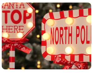 Detail of wooden Christmas stop signs with warm LED lights and red bows for festive decor