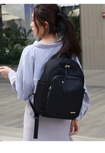 Foto lifestyle de una mujer con mochila de tela Oxford negra y cremalleras doradas