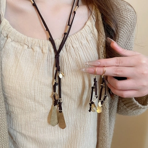 Detail view of bohemian necklace and earrings set with gold metal fringe and suede cord