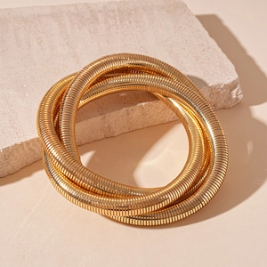 Minimalist gold textured metal wrap bracelet on a natural stone background