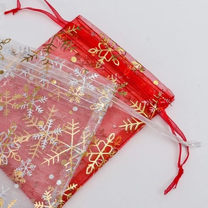 Macro shot of red and white organza gift bags with gold snowflake patterns and ribbons