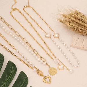 Flat lay of multiple gold chain necklaces with pearls and heart-shaped metal pendants
