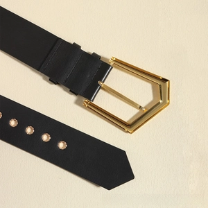 Macro shot of black leather belt with gold geometric buckle and metal-ringed eyelets