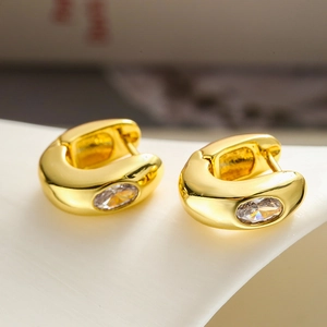 Élégantes créoles plaquées or avec zircon ovale sur un présentoir minimaliste