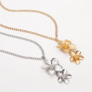 Close-up of gold and silver layered flower pendant necklaces with metal chains