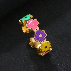 Macro detail of gold flower ring with colorful mint, purple, and yellow enamel petals