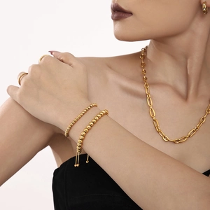 Luxury 4mm gold beaded stainless steel bracelet and jewelry set worn by a model
