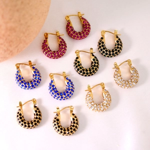 Close-up of gold-plated hoop earrings with colorful cubic zirconia on white silk