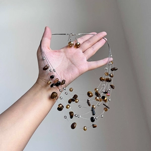 Hand holding crystal beaded Tiger Eye stone necklace and earrings jewelry set