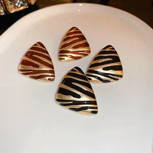 Gold-plated triangular earrings with animal print enamel and vintage metallic texture