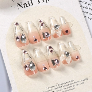 Macro view of coffin nails featuring 3D bows, pearls, and rhinestones on nude gradient base