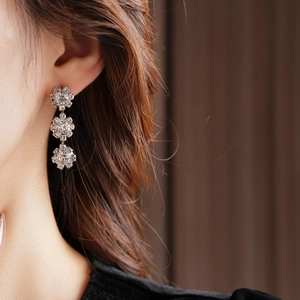 Close-up of sparkling silver floral drop earrings with rhinestones on a female model