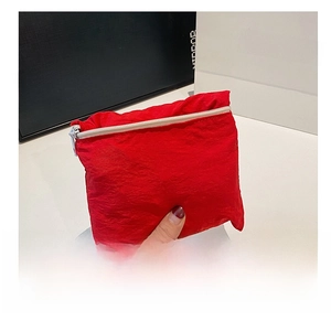 Close-up of a red nylon portable mini storage bag with a silver metal zipper closure