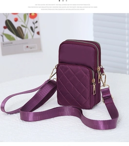 Detail of deep purple quilted nylon crossbody bag showing three layered zipper compartments