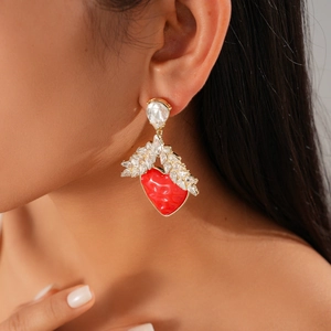Detail of model wearing red heart drop earrings with gold metal and sparkling crystals