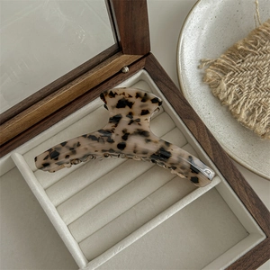 Detail of large acetate hair claw clip with light leopard pattern in beige jewelry box