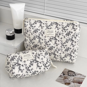 Detail of floral quilted makeup bag set featuring a rectangular pouch and round handle bag