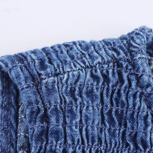 Macro detail of washed denim fabric with honeycomb smocking and textured pleat design
