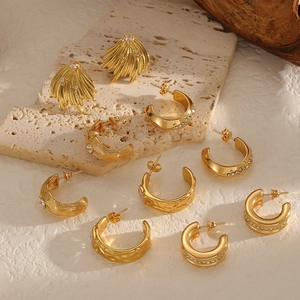 Boucles d'oreilles vintage en titane doré avec zircons sur une surface en pierre